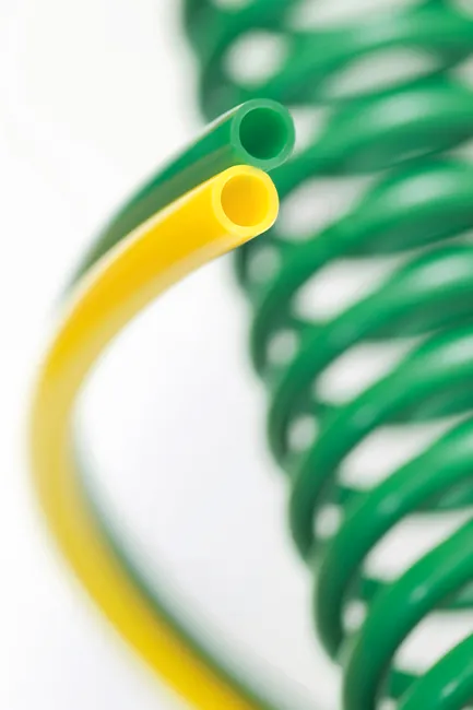 Ein gelber und ein Grüner Pneumatikschlauch als Schlauchspirale