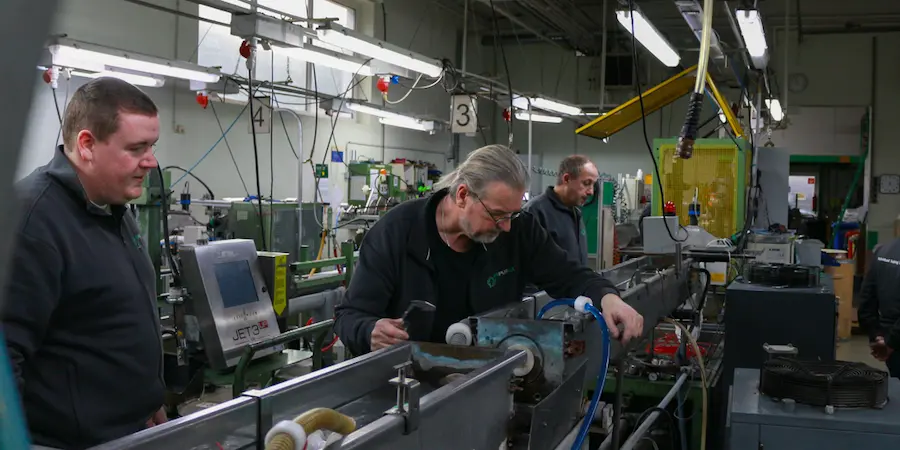 Drei Männer bei der Schlauchentwicklung an der Extrusionslinie