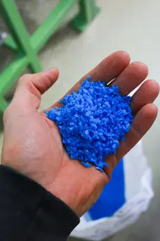 A hand full of blue rerganulate for regranulated tubing